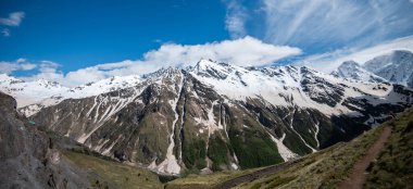 Mountain landscape. Caucasus mountains. Svaneti. Georgia. Panoramic view from the hill on mountains with hiking path against cloudy sky.