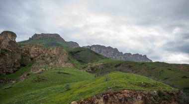 Summer mountain landscape. Amazing view of the valley and lush green pastures in the Caucasus, Georgia. Surrounded by high mountain ranges. Cloudy and rainy day in spring, low storm clouds.