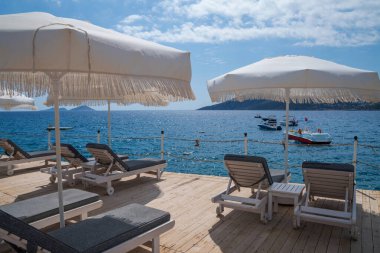 Plaj tatil beldesi, deniz yaz tatili konsepti. Şemsiyeli tahta güneşlikler. Plaj otelinde bir dizi güneşlik..