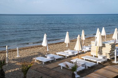 Plaj tatil beldesi, deniz yaz tatili konsepti. Şemsiyeli tahta güneşlikler. Plaj otelinde bir dizi güneşlik..