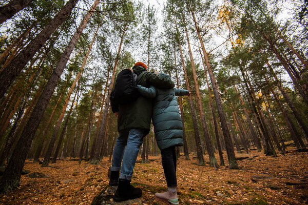 Couple of lovers man and woman in a pine forest. autumn background. Backpacking walk through a beautiful forest.