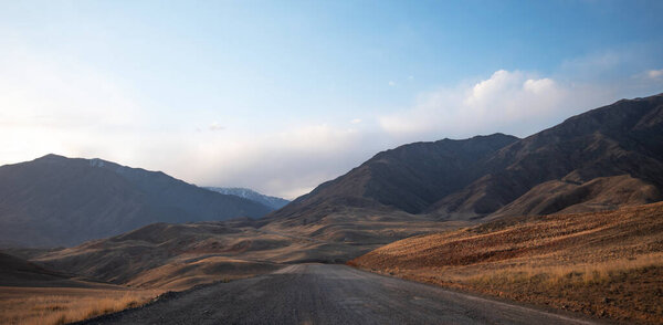 Горы Куньлунь в Китае. Горный пейзаж. Природные паттерны. Загородная дорога, проходящая через горы на закате.