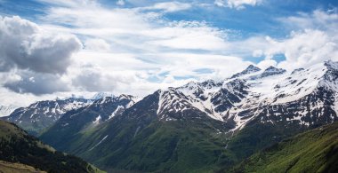 Yeşil ormanlık dağlar ve yüksek dağların etrafındaki karlar ve güzel bir gökyüzü bir yaz günü. Georgia.