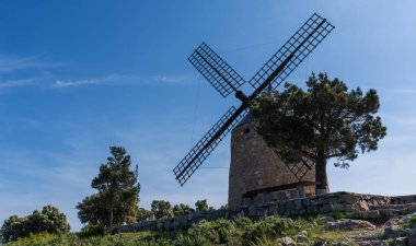 Tepedeki tipik eski İspanyol yel değirmenleri, İspanya 'nın yeşil manzarasıyla çevrilidir..