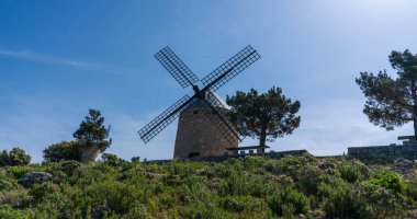 Tepedeki tipik eski İspanyol yel değirmenleri, İspanya 'nın yeşil manzarasıyla çevrilidir..