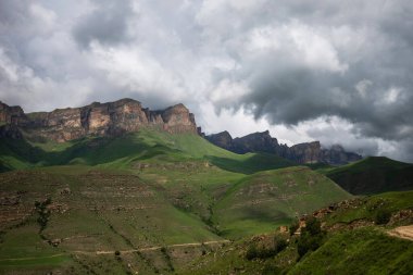 Kayalık tepeli yeşil tepeler. Bulutlar yamaçlara gölge düşürür. Güzel bulutlu gökyüzü.