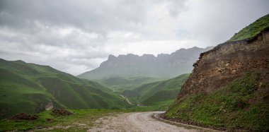 İlkbaharda bulutlu ve yağmurlu bir gün, düşük fırtına bulutları. Dağ manzarası. Vadinin muhteşem manzarası ve Georgia 'nın yemyeşil otlakları. Vadi yüksek sıradağlarla çevrili..