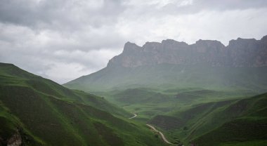 İlkbaharda bulutlu ve yağmurlu bir gün, düşük fırtına bulutları. Dağ manzarası. Vadinin muhteşem manzarası ve Georgia 'nın yemyeşil otlakları. Vadi yüksek sıradağlarla çevrili..