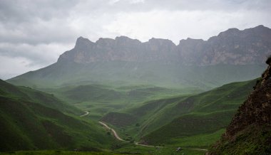 İlkbaharda bulutlu ve yağmurlu bir gün, düşük fırtına bulutları. Dağ manzarası. Vadinin muhteşem manzarası ve Georgia 'nın yemyeşil otlakları. Vadi yüksek sıradağlarla çevrili..