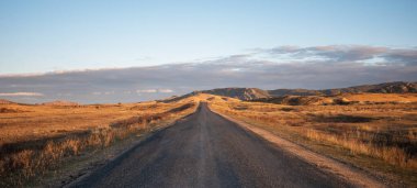 Sonbahar manzarası boyunca bir tepe üzerinde düz bir kır yolu. Otlak arazisi ve tepeler. Kırsal alanlar.