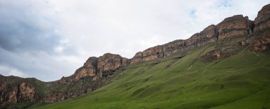 İlkbaharda bulutlu ve yağmurlu bir gün, düşük fırtına bulutları. Dağ manzarası. Vadinin muhteşem manzarası ve Georgia 'nın yemyeşil otlakları. Vadi yüksek sıradağlarla çevrili..