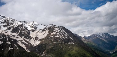 Summer view of the mountains with snowy peaks. Beautiful nature vacations, hiking, travel to nature destinations. View of the snowy rocky massif. Tourist attraction. World of beauty.