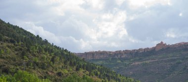 Tarragona 'nın Ciurana köyünün manzarasında kayalık dağlar ve gökyüzünde bulutlar var..