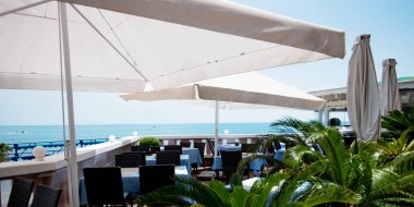 Açık terasta manzaralı bir restoran ya da kafe. Masalar mavi keten tabaklarla dolu. İtalyan tarzı. Turizm ve seyahat. Hayatın tadını çıkarıyorum. Güzel yerler..