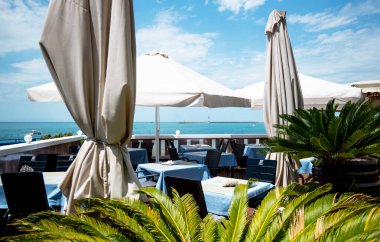 Açık terasta manzaralı bir restoran ya da kafe. Masalar mavi keten tabaklarla dolu. İtalyan tarzı. Turizm ve seyahat. Hayatın tadını çıkarıyorum. Güzel yerler..