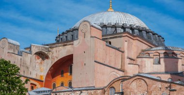 Sofya 'nın İstanbul' daki kendine özgü mimarisi muazzam kubbesini, yarım kubbesini ve daha küçük dış yapılarını arkaplan olarak açık mavi gökyüzünü sergiliyor.