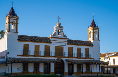 Beyaz cepheli büyük bir İspanyol kilisesi. Sarı süslemeli, üzerinde mavi gökyüzü bulunan ve geleneksel Endülüs mimarisini somutlaştıran ikiz çan kuleleri sergiliyor.