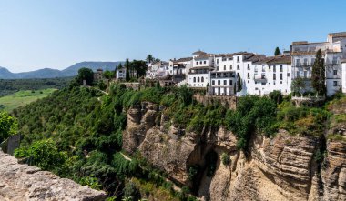 Dramatik bir uçurumun tepesine tünemiş, Akdeniz 'de bir kasabanın beyaz binaları güneşlenir, yemyeşil vadilere ve berrak mavi gökyüzünün altındaki kayan tepelere tepeden bakar.