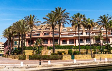 Palmiye ağaçlarıyla çevrili lüks Akdeniz teras çatılı daireler, sakin bir yerleşim bölgesinde kıyı İspanyol mimarisi sergileniyor..