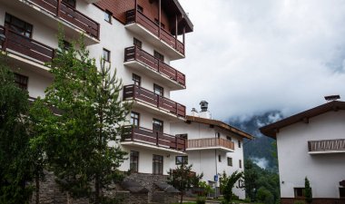 Beyaz duvarları ve ahşap balkonları olan dağ pansiyonları, canlı yeşillikler arasında yuva yapar. Dağ havasının puslu kucaklaması, dingin çevreye biraz gizem katar.