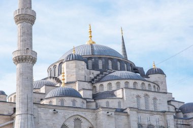 Görkemli kubbe ve bir caminin incecik minaresi, zarif bir şekilde gökyüzüne yükselir, onların karmaşık detayları güneşin altında parıldayan altın finansmanlarla vurgulanır..