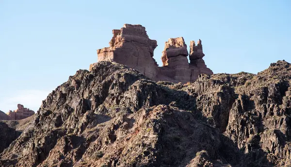 stock image The rugged beauty of a desert landscape is captured as the sun casts its glow on sandstone spires, which stand proudly against a clear, pale sky.