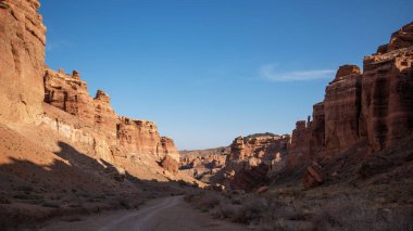 Tozlu bir yol dramatik bir kanyon boyunca ilerleyen kırmızı kumtaşı uçurumları, yumuşak bir öğleden sonra ışığında yıkanan, vahşi doğada macera ve yalnızlık hissi uyandıran