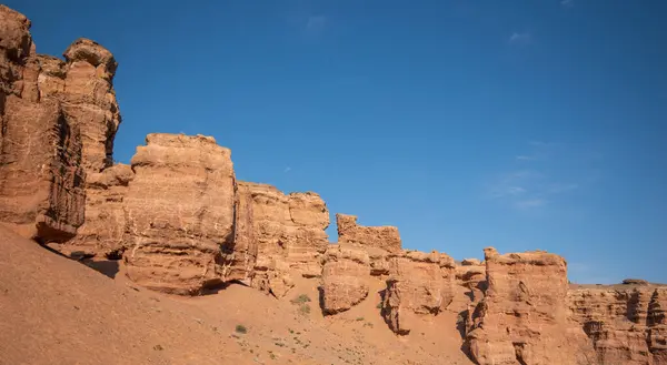 stock image a striking range of massive red sandstone formations under a vast blue sky, hinting at a tranquil desert setting in the warm, gentle light of a late summer afternoon