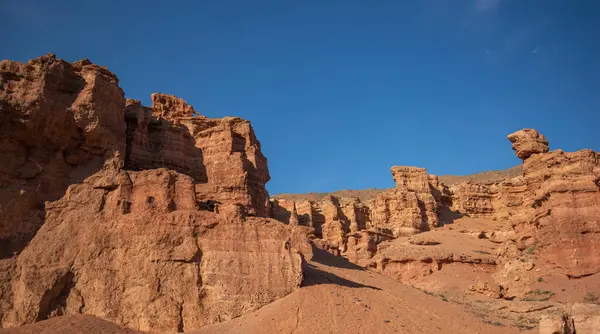 stock image a striking range of massive red sandstone formations under a vast blue sky, hinting at a tranquil desert setting in the warm, gentle light of a late summer afternoon