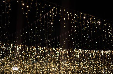 Koyu bir zemin üzerinde parıldayan sayısız sarı ışık iplikçiklerinin yakın plan görüntüsü, birçok odak dışı ışık noktasıyla bir bokeh etkisi yaratır..