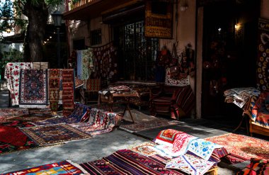 Cobblestone caddesinde renkli, karmaşık dokuma halıları ve tekstil ürünleri olan canlı bir market tezgahı. Geleneksel şablonlar, şehrin tarihi bir bölgesinde canlı bir atmosfer yaratıyor..