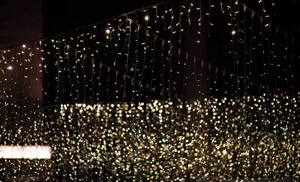 крупным планом многочисленные нити мерцающих желтых волшебных огней на тёмном фоне, создавая эффект боке со многими нефокусированными точками света.