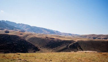 Geniş, geniş bir gökyüzü olan geniş, yuvarlanan tepeler. Sonbaharın sonunda ya da kışın başında dağların toprak tonları, seyrek bitki örtüsü ve uzak dağlarda karla kaplı.