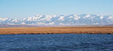 Su kütlelerinin durgunluğunun, engin mavi gökyüzü tarafından çerçevelenmiş, uzak, karla kaplı dağların engebeli ihtişamının ön plana çıktığı zıt manzaralar.