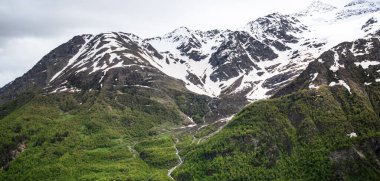 Summer view of the mountains with snowy peaks. Beautiful nature vacations, hiking, travel to nature destinations. View of the snowy rocky massif. Tourist attraction. World of beauty.