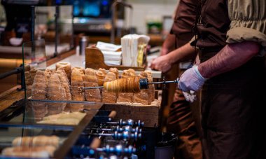 Street food of Prague. Traditional national Czech sweet food. Tubes of sweet dough, cooked on an open fire. Popular dessert in Prague. Grilled food. Manufacturer trdelnik. Selective focus. clipart