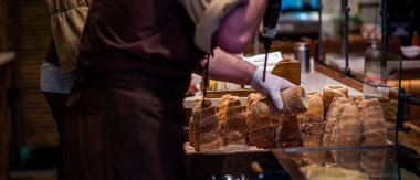 Geleneksel lezzetli Trdelnik yapan aşçının eli. Sokak yemeği. Prag 'daki sokak pazarındaki Trdelnik pastanesinde. Geleneksel Çek çörekleri rulo ve ızgara hamur işleri.