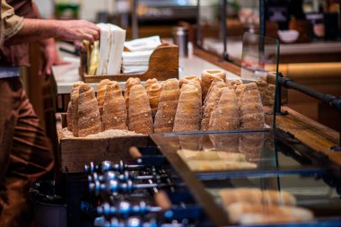 Geleneksel lezzetli Trdelnik yapan aşçının eli. Sokak yemeği. Prag 'daki sokak pazarındaki Trdelnik pastanesinde. Geleneksel Çek çörekleri rulo ve ızgara hamur işleri.