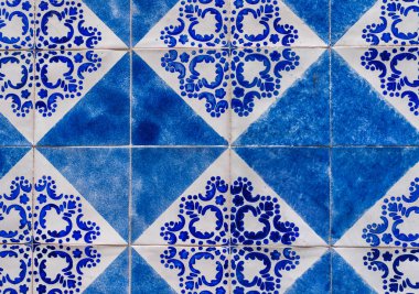 Geleneksel mavi ve beyaz seramik fayanslardan oluşan çarpıcı bir desen, Akdeniz dekoratif sanatının bir imzası olan geometrik şekillerin ve çiçeklerin bir füzyonunu gösteriyor.