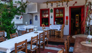 Canlı kırmızı çiçekler ve yeşilliklerle süslenmiş beyaz sandalyeleri ve masaları olan büyüleyici bir açık hava kafesi. Davetkar ortam, sakin bir yemek ya da kahveden zevk almak için mükemmel..