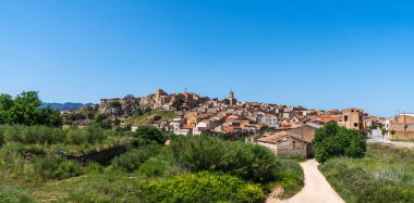 Terakotta çatılı evleri olan büyüleyici bir tepe köyü açık mavi gökyüzünün altında güneşleniyor. Tuhaf yerleşim yeri yemyeşil ve manzaralı kırsal alanlarla çevrili..
