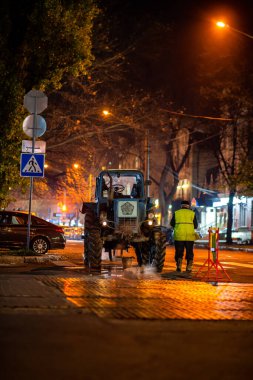 Bir traktör ve bir işçi, yol onarımı süreci. Ukrayna, Mykolaiv