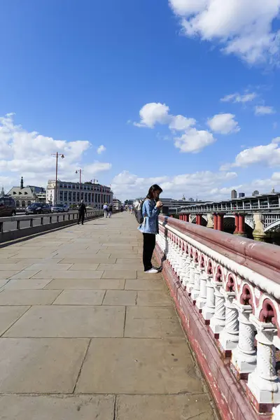 stock image London - 06 10 2022: Girl looks at mobile phone on Blackfriars Bridge.