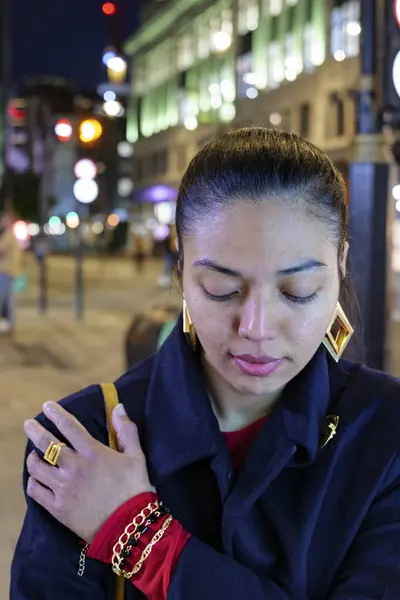 stock image London - 06 11 2022: Evening girl touches her shoulder and looks down on New Oxford St