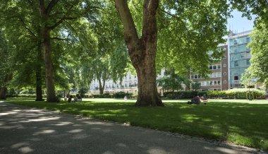 Londra - 06 14 2022: İnsanlar St. George Meydanı 'ndaki çimlerin üzerinde dinleniyor