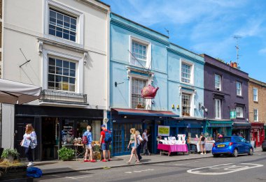 Londra - 06 17 2022: Portobello Yolu 'nda yürüyen insanlar. İşaret olarak çaydanlığı olan bir dükkanın önünde.