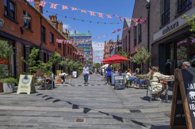Londra - 06: 20 2022: Chelsea 'deki Pavilion Bulvarı' nda bir kafe masasının arasında bir kadın yürüyor.