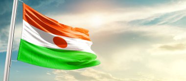 Niger waving flag in beautiful sky with sun