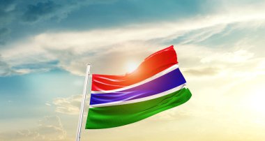The Gambia waving flag in beautiful sky with sun