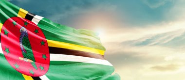 Dominica waving flag in beautiful sky with sun